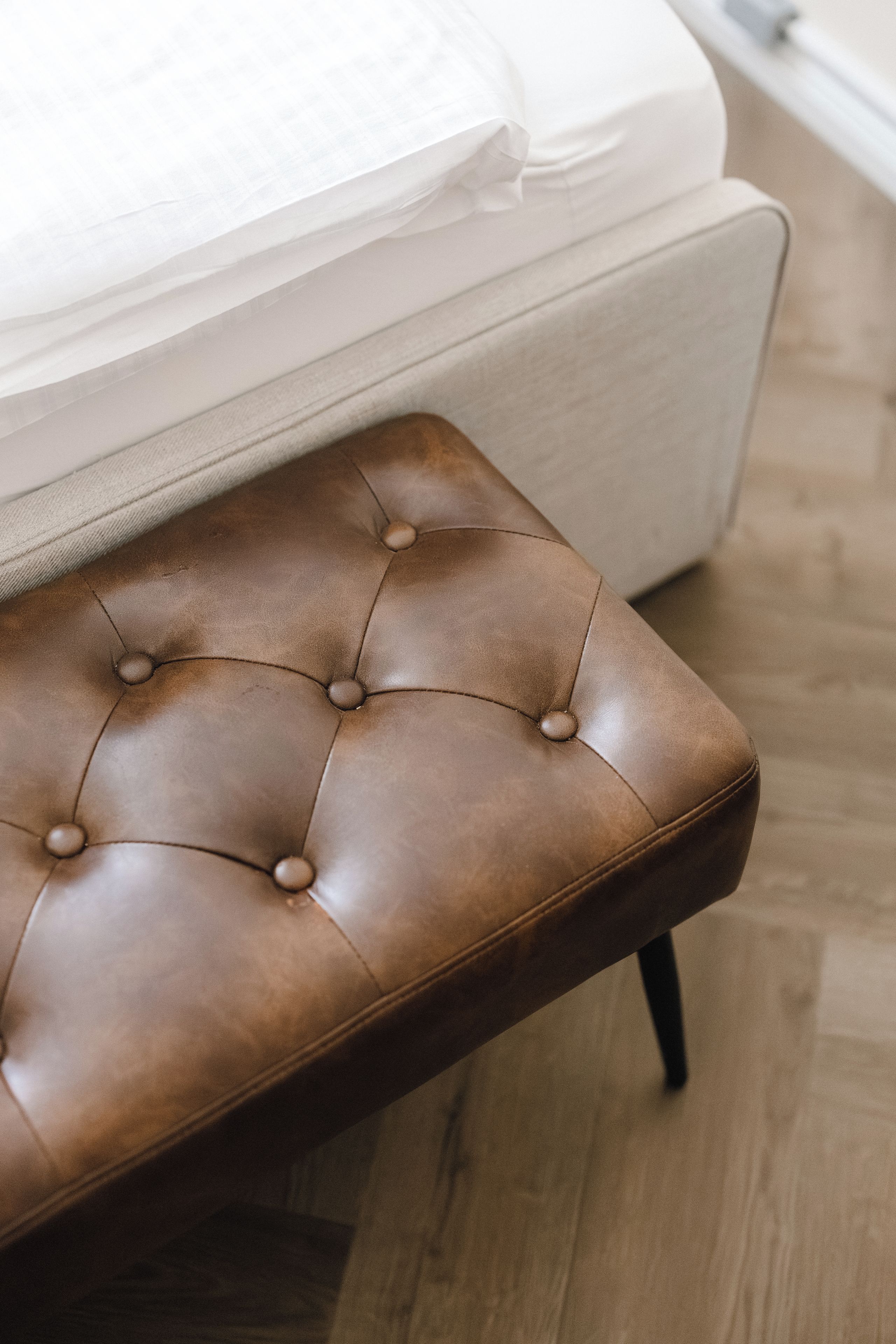 A tufted bench with a cushioned seat and four legs.
