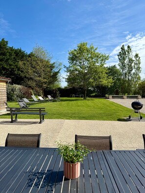 Un espace patio avec des sièges d’extérieur, une pelouse et un barbecue.