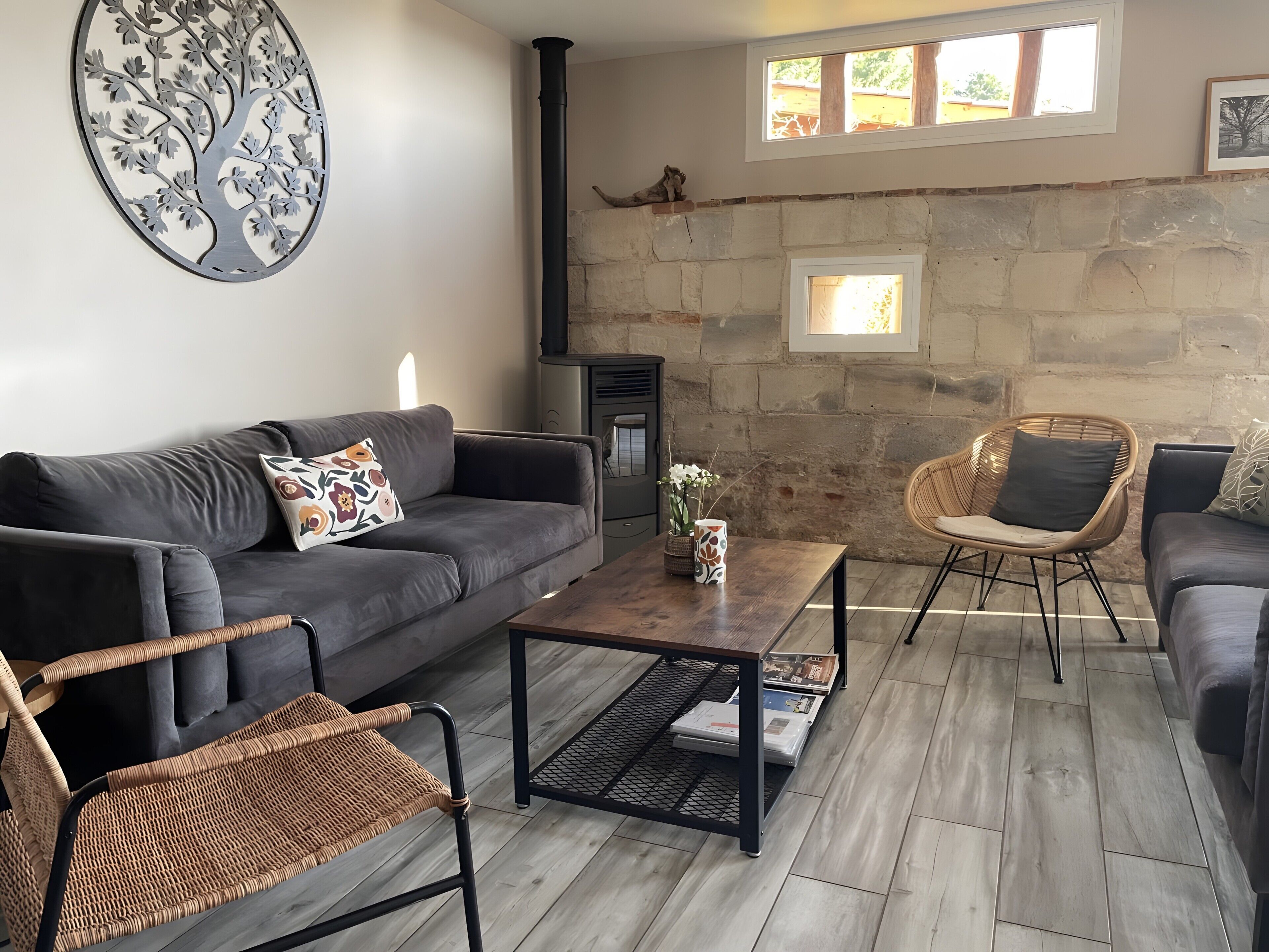 Una sala de estar con un sofá, dos sillones de mimbre, una mesita de centro y una chimenea.