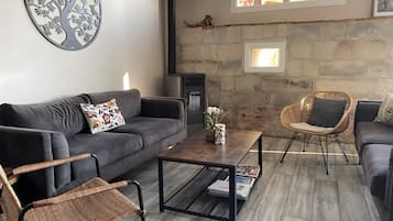 Una sala de estar con un sofá, dos sillones de mimbre, una mesita de centro y una chimenea.