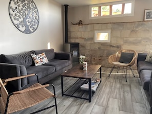 A living room with a sofa, two wicker chairs, a coffee table, and a fireplace.