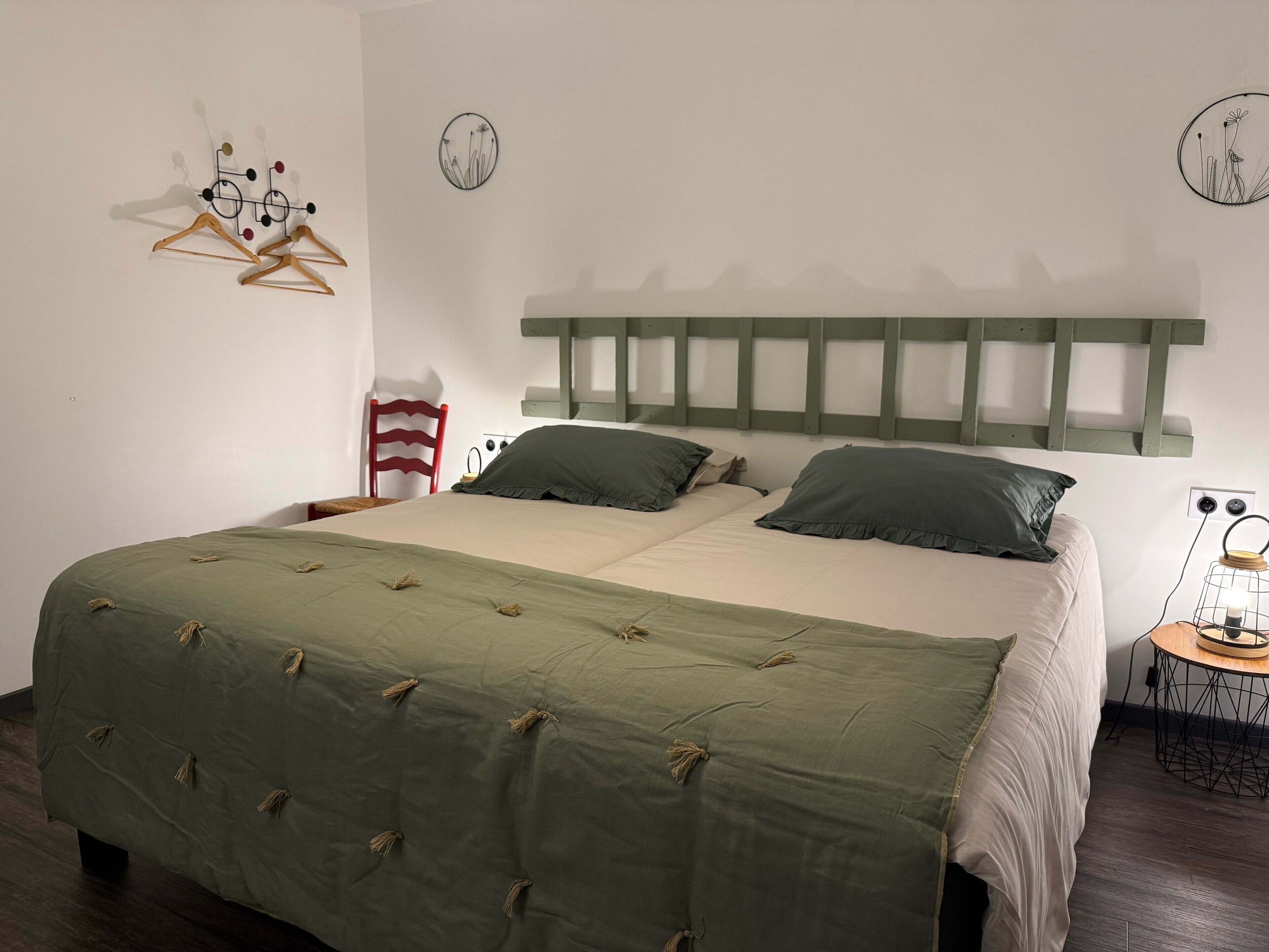 Une chambre à coucher comprenant un lit, une chaise, une table de chevet avec une lampe et des œuvres d’art murales.