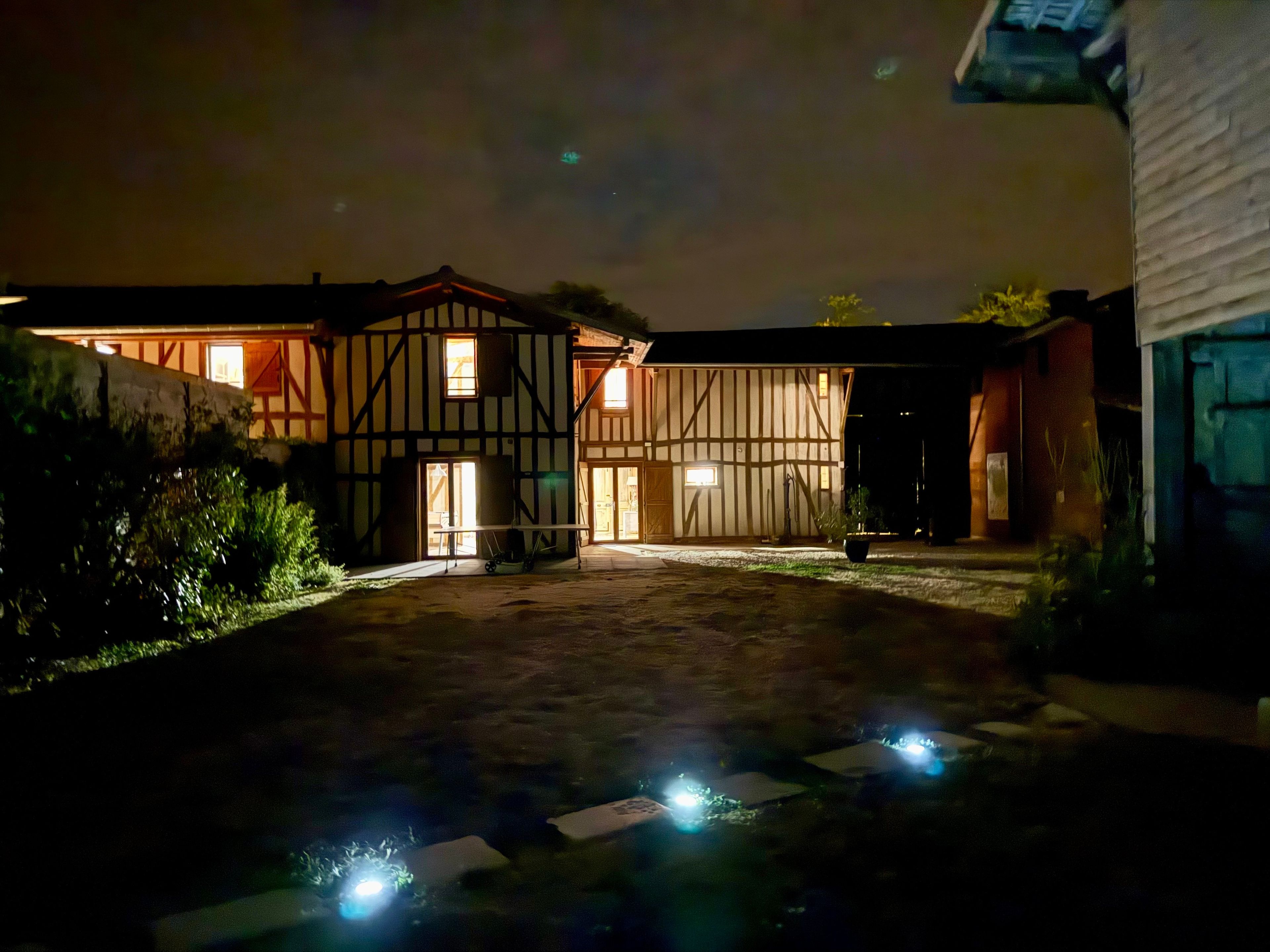 Edifici tradicional amb entramat de fusta i un pati, il·luminat per llums artificials.