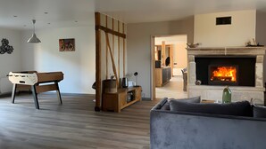 Ein Wohnzimmer mit Kamin, einer Couch, einem Holztisch und einem Essbereich im Hintergrund.