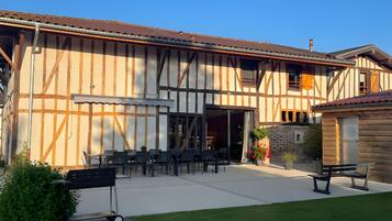 A building with a large patio area, outdoor seating, and a small garden.