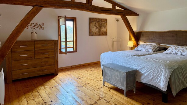 Ein Schlafzimmer mit Holzboden, einem Bett mit Kopfteil, einem Schminktisch, einem kleinen Tisch und einem Fenster mit Aussicht.