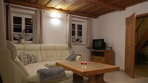 Een gezellige woonkamer met een bank, een houten salontafel en een televisie op een houten dressoir.