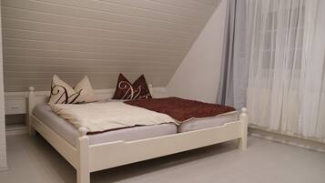 A white bed in a room with sloped ceilings and a white floor.