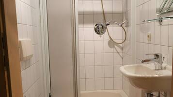 A bathroom with a toilet, shower, and sink.