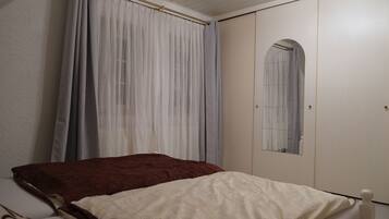 A bedroom with a bed, a wardrobe, and a mirror.