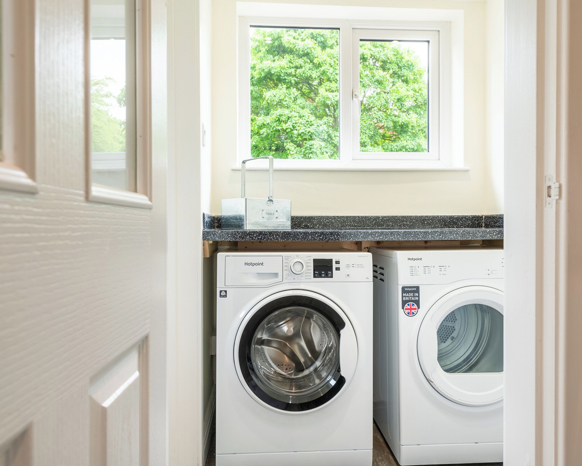 A laundry room with two front-loading washing machines and a window above them.