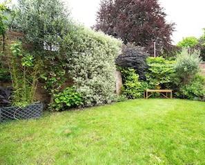 A well-maintained garden with a variety of plants and a wooden bench. - 59 Garfield Road (Scarborough)