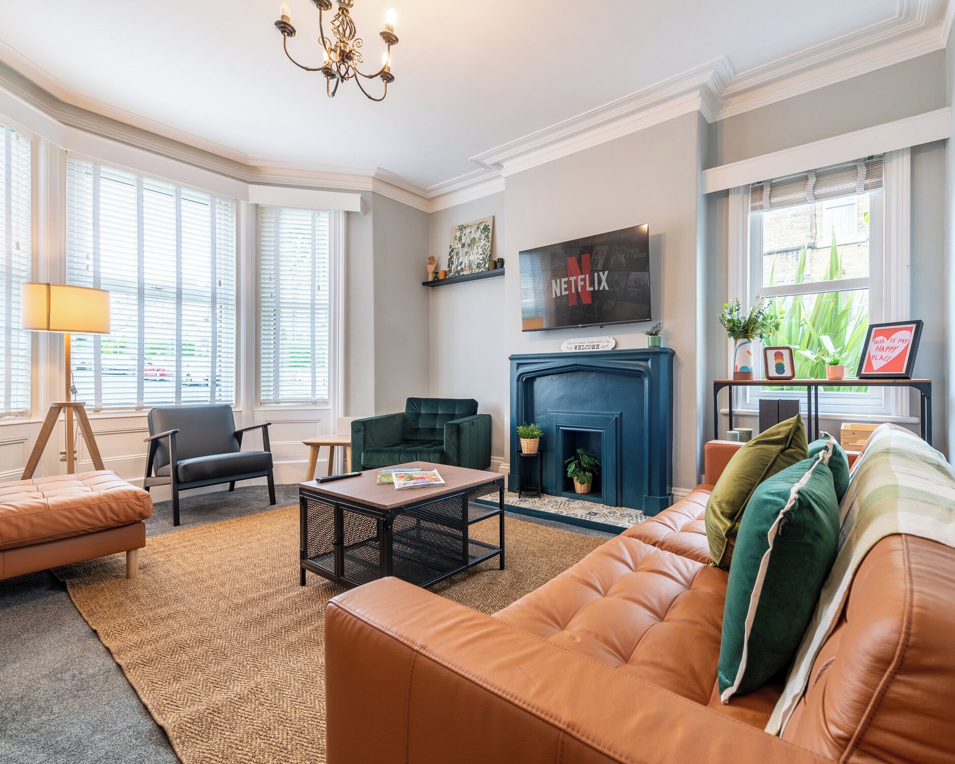 A living room with a fireplace, a sofa, a coffee table, and a television mounted above the fireplace.
