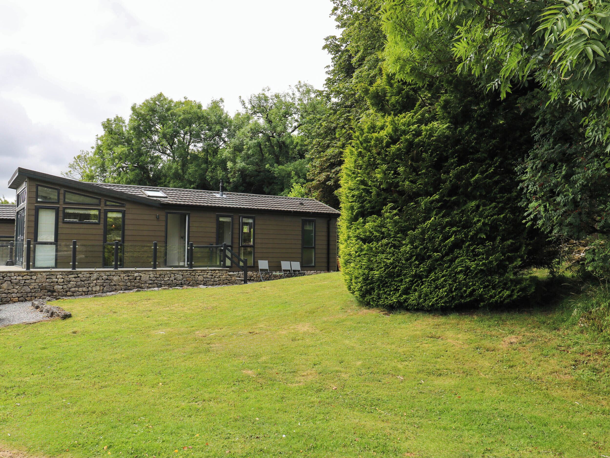 A modern building with a stone foundation, large windows, and a grassy lawn.