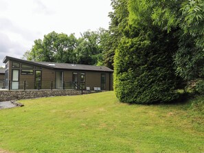 A modern building with a stone foundation, large windows, and a grassy lawn. - Dales Retreat (Skipton)