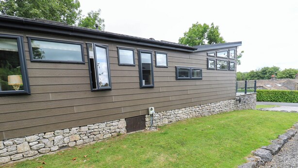 A modern two-story building with a stone foundation and a flat roof. - Dales Retreat (Skipton)