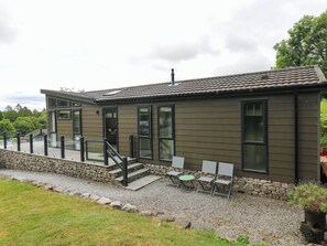 A modern building with a stone foundation, a covered patio with outdoor seating, and a clear sky. - Dales Retreat (Skipton)