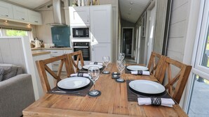A dining table set for four with a view of the kitchen and a balcony. - Dales Retreat (Skipton)