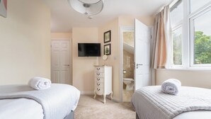 A bedroom with two beds, a television, a dresser, and a bathroom visible through an open door. - The Ravines (Scarborough)