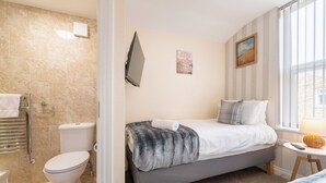A bedroom with a bed, a bedside table, a window, and a view of the outside. - The Ravines (Scarborough)