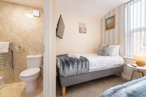 Quarto com cama, mesa de cabeceira, janela e vista para o exterior.
