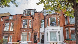 A row of red brick terraced houses with bay windows and white trim. - The Ravines (Scarborough)