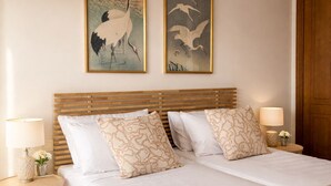 A double bed with a wooden headboard, two bedside tables with lamps, a beige rug, and two wall-mounted paintings of birds. - Deluxe 2-Bedroom Apartment (El Ejido)