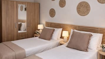 Habitación de hotel con dos camas, un armario de madera, un espejo y decoración en la pared.