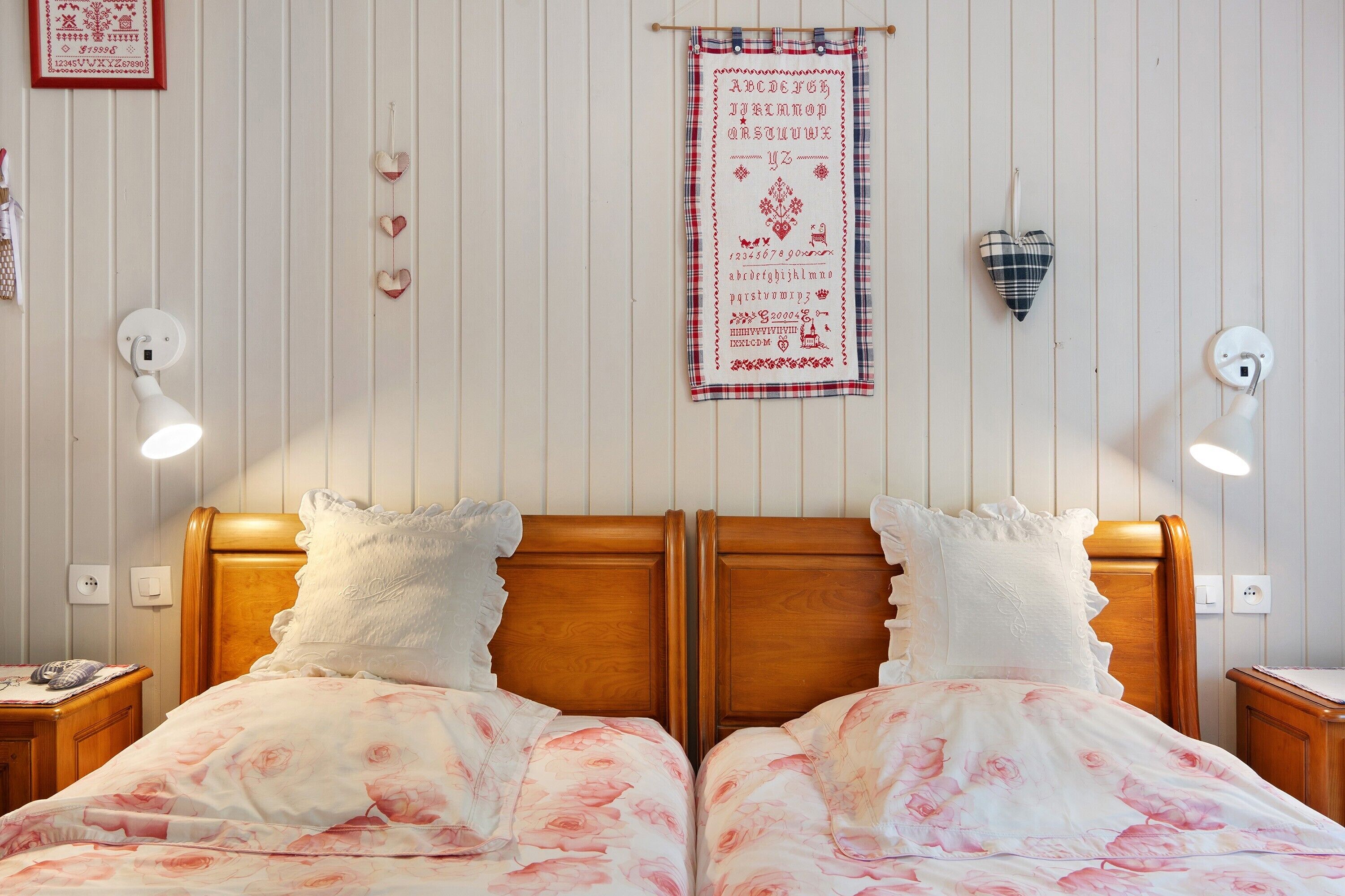 A double bed with floral bedding, a wooden headboard, and two bedside lamps.
