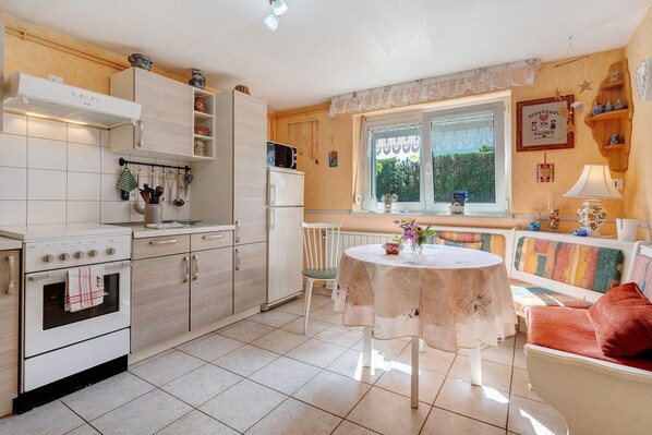A kitchen with a dining area, including a table and chairs, a refrigerator, and a stove.