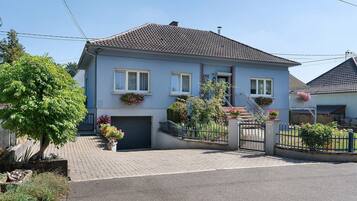 A two-story residential building with a tiled roof, a front garage, and a gated entrance.