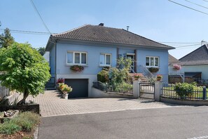 A two-story residential building with a tiled roof, a front garage, and a gated entrance.