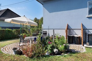 Un pati amb una taula i caires, una planta en test i una petita zona de jardí.