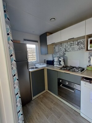 A compact kitchen with a built-in gas stove, a sink, and a refrigerator.