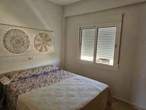 A bedroom with a bed, a window with blinds, and two wall decorations. - Las Perlas Development, Las Marinas Highway (Denia)