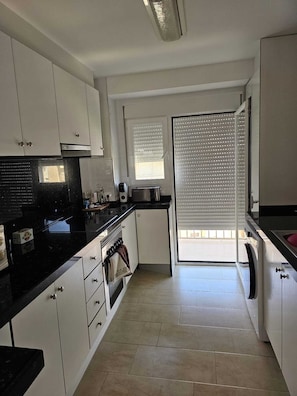 A kitchen with white cabinets, a black countertop, and a tiled floor. - Las Perlas Development, Las Marinas Highway (Denia)