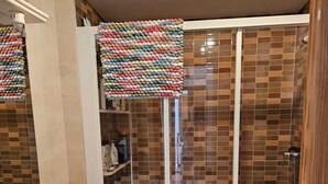 Un baño con cabina de ducha de vidrio, lavabo blanco y retrete.