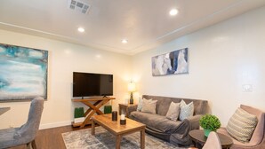 Ein Wohnzimmer mit Flachbildfernseher, Sofa, Couchtisch und Sessel.