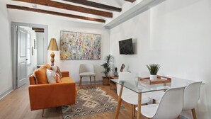 Ein modernes Wohnzimmer mit einer Couch, Sesseln, einem Glastisch und einem Gemälde an der Wand.