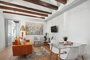 A modern living room with a sofa, chairs, a glass table, and a painting on the wall. - Uptown Retreat w/ driveway steps from Magazine St. Washer and dryer + Backyard! (New Orleans)