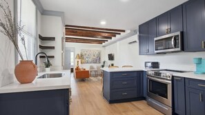 A modern kitchen with dark cabinetry, a built-in microwave, and a stainless steel oven. - Uptown Retreat w/ driveway steps from Magazine St. Washer and dryer + Backyard! (New Orleans)