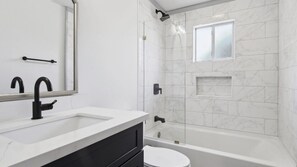 A modern bathroom with a white sink, black faucet, and a bathtub. - Uptown Retreat w/ driveway steps from Magazine St. Washer and dryer + Backyard! (New Orleans)