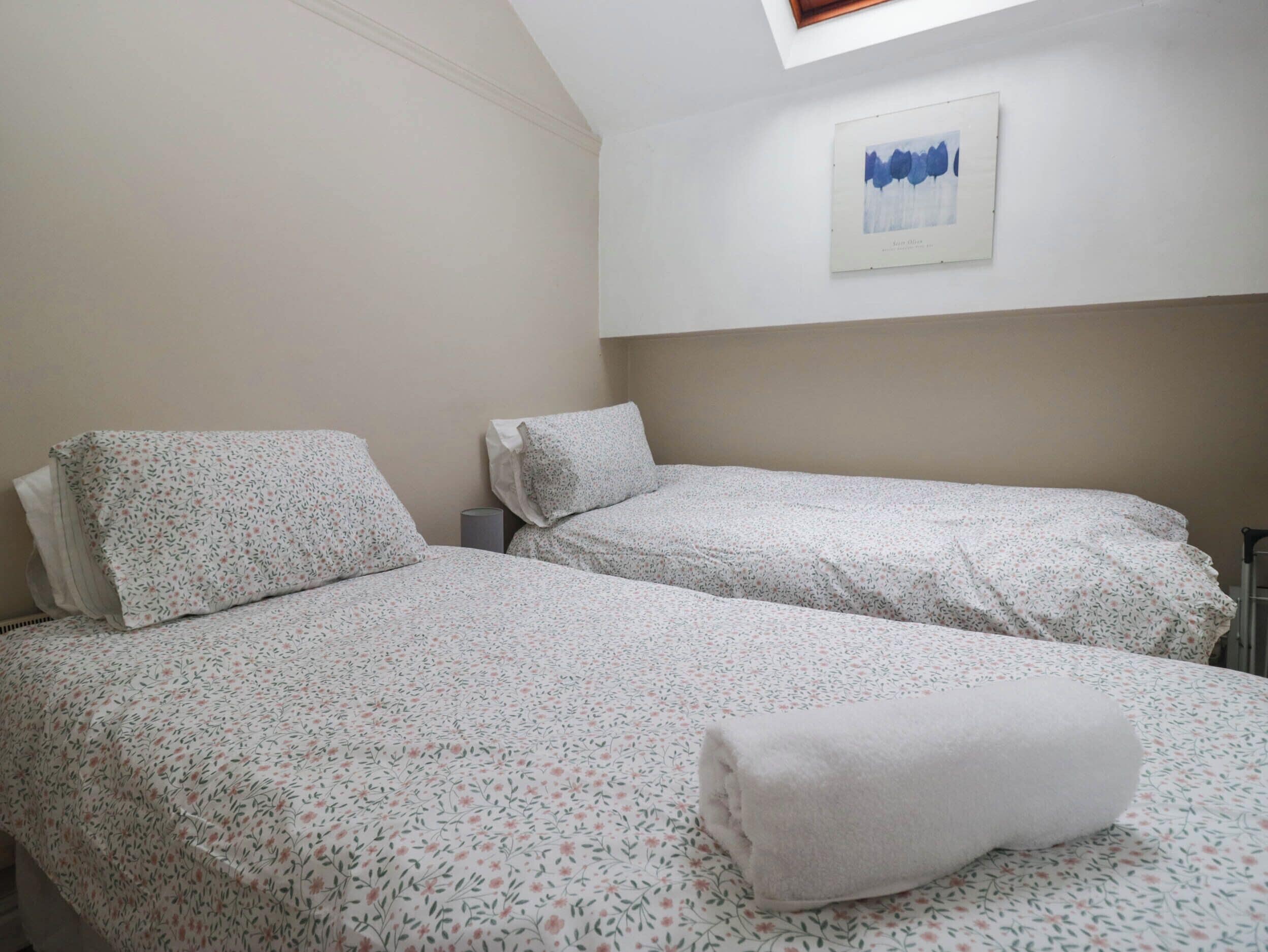Habitación doble con dos camas, un tragaluz y una obra de arte enmarcada en la pared.