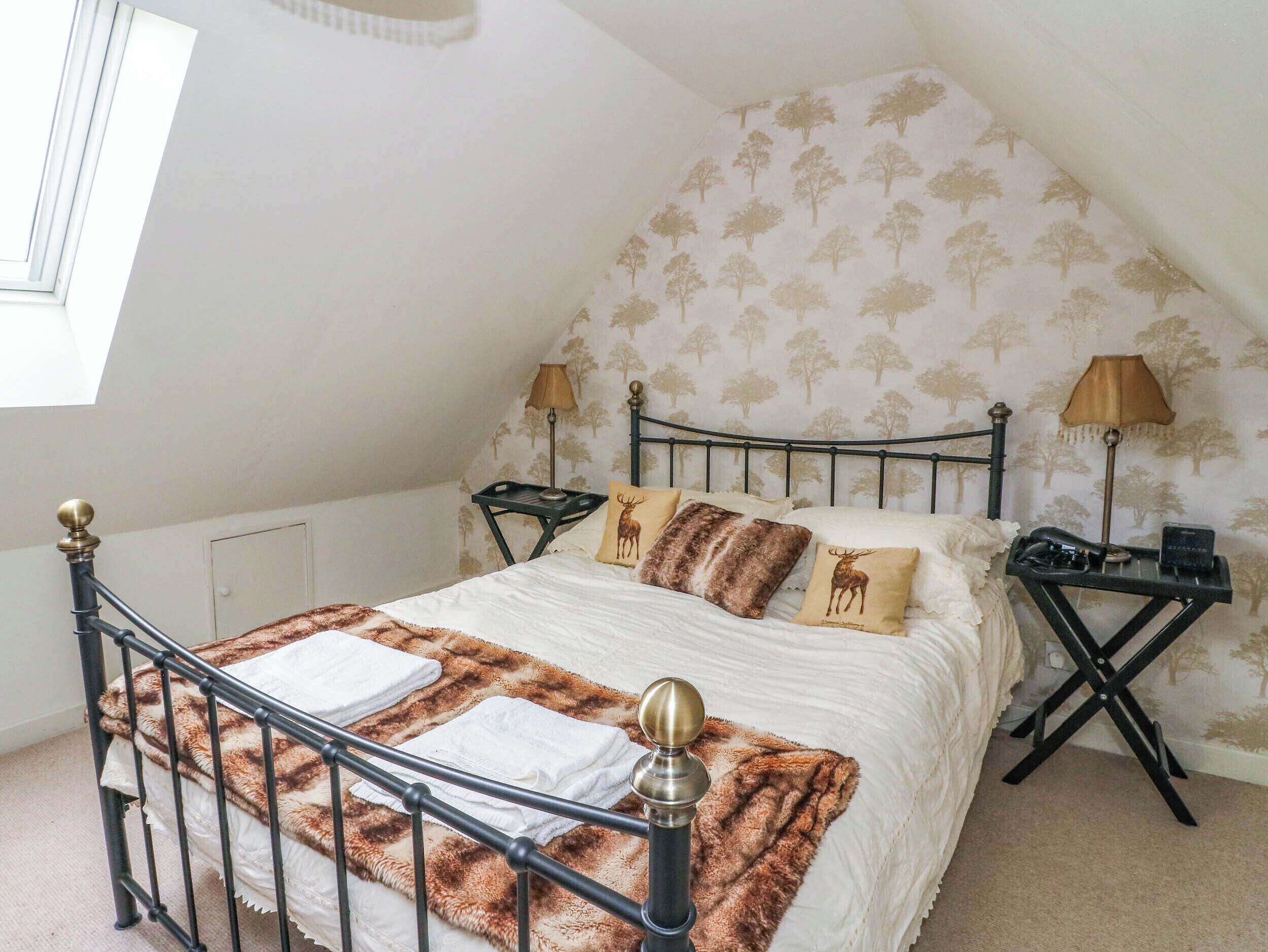 A bedroom with a bed, two bedside tables, a lamp, and a window.
