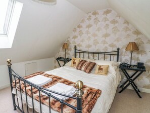 Een slaapkamer met een bed, twee nachtkastjes, een lamp en een raam.