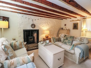 A cozy living room with a fireplace, a sofa set, a small table, and a lamp.
