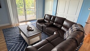 Ein Wohnzimmer mit einem Ecksofa, einem Couchtisch und einem Deckenventilator.