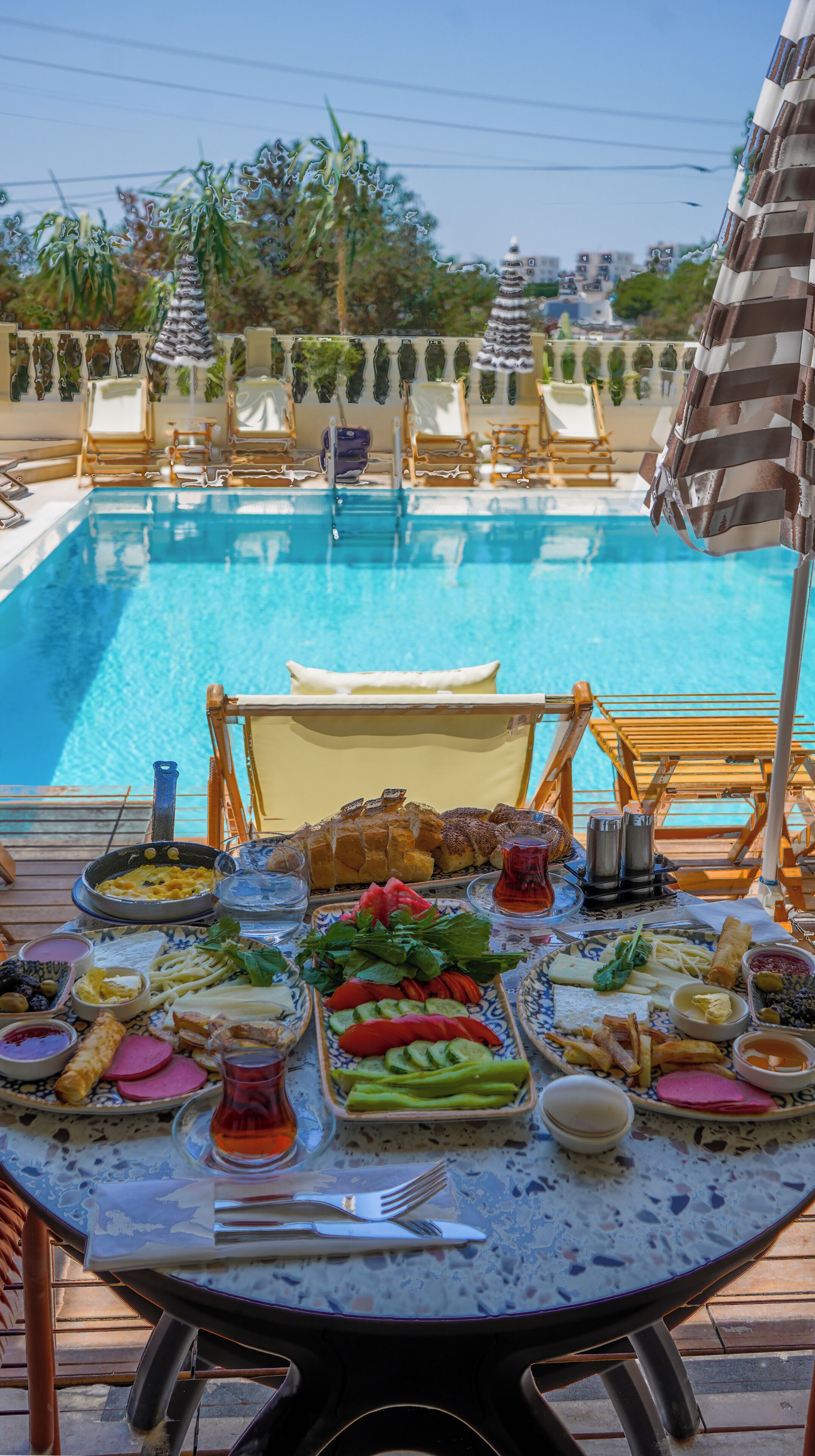 Zona de comedor junto a la piscina con una mesa preparada para una comida, con vistas a una pileta.