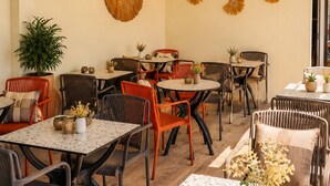 A dining area with multiple tables and chairs, decorative wall art, and pendant lighting. - Ciello Hotel (Bodrum)