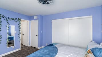 Un dormitorio con cama, ventilador de techo y una puerta.